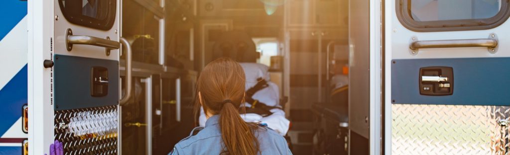 Paramedic looks into the back of an open ambulance.